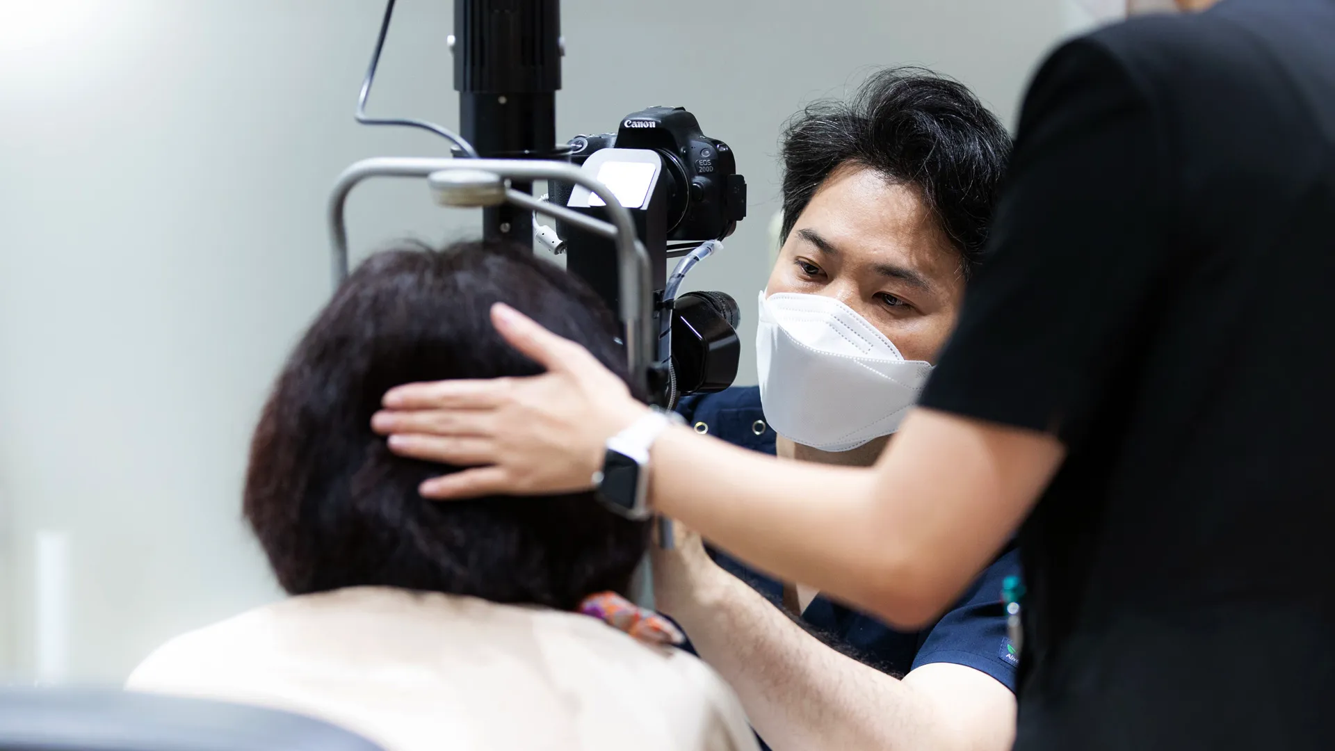 細隙灯検査で医療スタッフが患者の頭を支えている様子